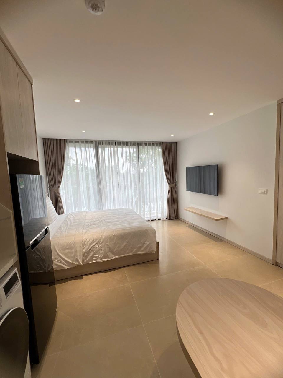 Studio homestay - giường đôi gỗ sáng, ga trắng sọc, TV treo tường, tủ quần áo gỗ