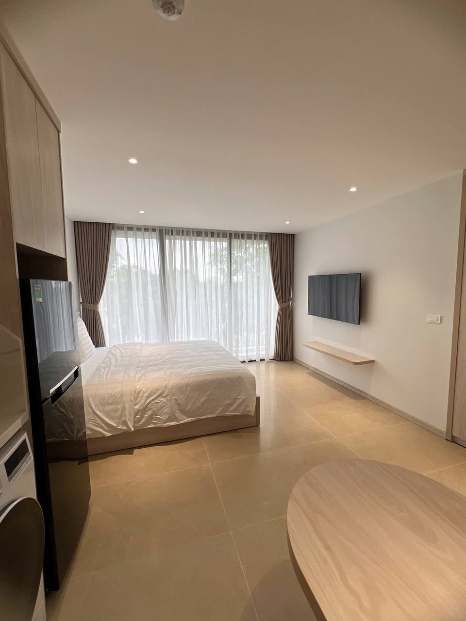 Studio giường đôi - tủ quần áo gỗ sáng, đèn ngủ, tranh đen trắng châu Âu treo tường